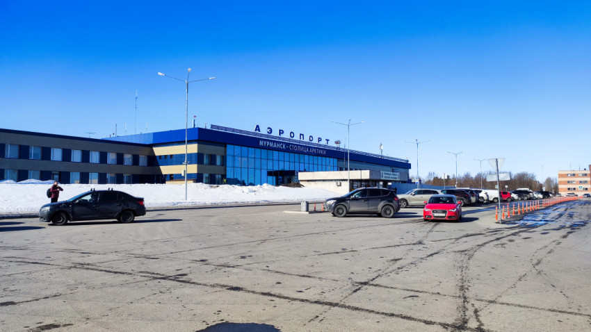 Фасад здания аэропорта Мурманска с парковкой и автомобилями