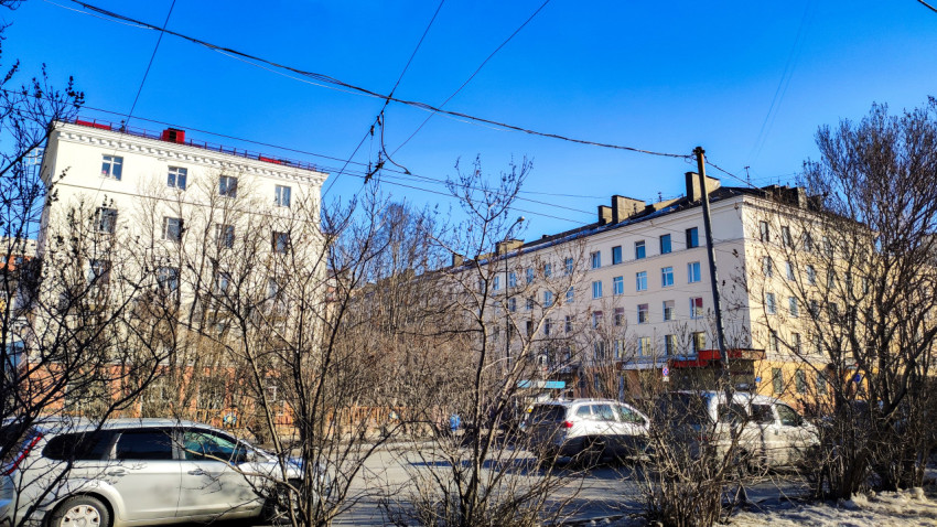 Вид на жилые дома за деревьями на фоне синего неба