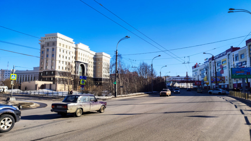 Улица в центре Мурманска с движением транспорта и торговыми зданиями