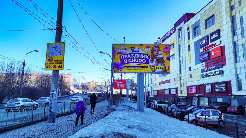 Рекламные щиты и торговый центр на улице в Мурманске зимой