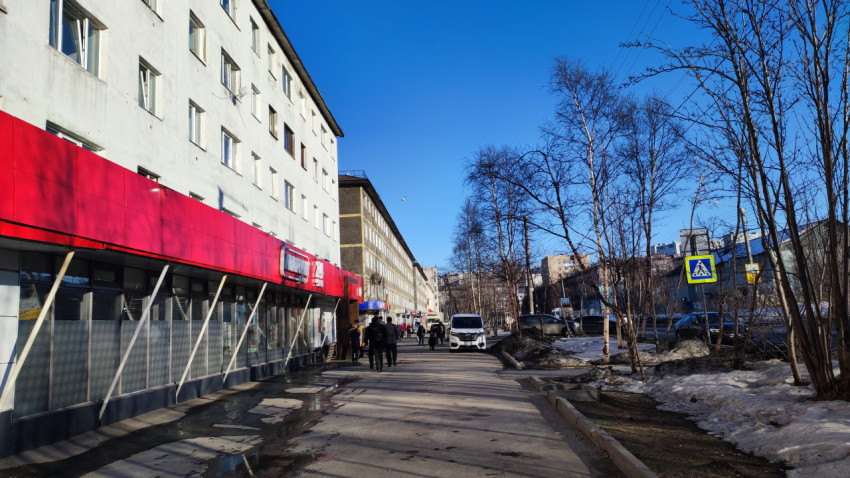 Пешеходная улица с магазинами, жилыми домами и прохожими в городском районе