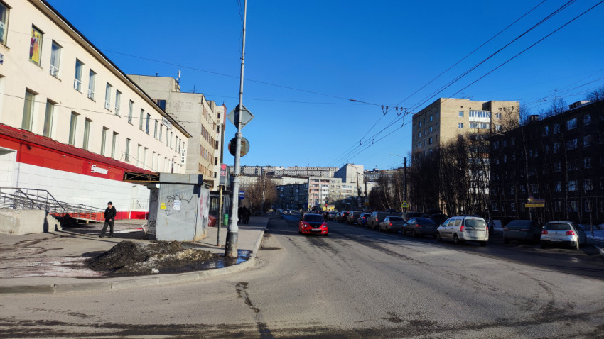 Городская улица с жилыми домами, магазинами и припаркованными автомобилями