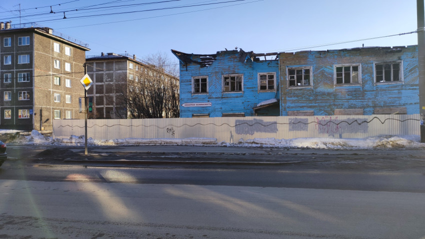 Заброшенное двухэтажное здание с разрушенной крышей, окружённое забором