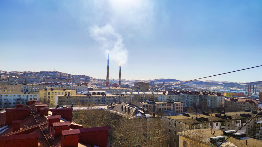 Городской пейзаж с дымящимися трубами на фоне гор