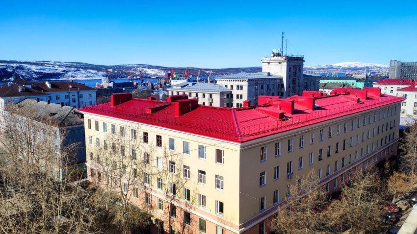 Жилой дом с красной крышей на фоне городского пейзажа