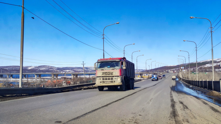 Грузовые и легковые автомобили на дороге возле моста через залив