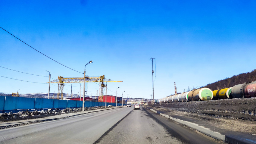 Дорога с движением транспорта вдоль промышленных объектов и железнодорожных цистерн