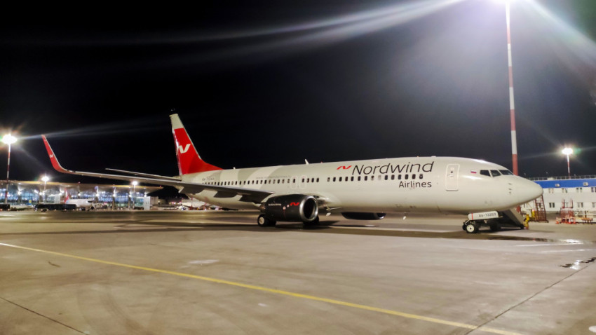 Пассажирский самолет авиакомпании Nordwind Airlines на перроне аэропорта ночью