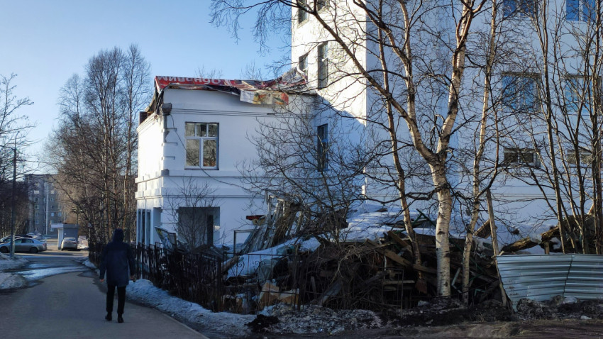 Фасад здания с обломками и мусором у стены в городском районе