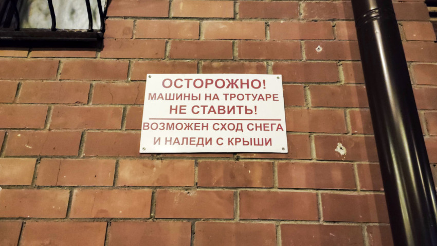 Предупреждающая табличка на кирпичной стене с надписью об опасности