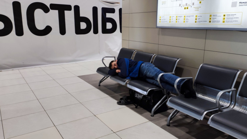 Пассажир спит на скамейке в зоне ожидания аэропорта
