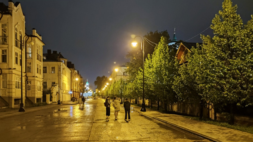 Ночная улица с фонарями и людьми на фоне архитектурного здания