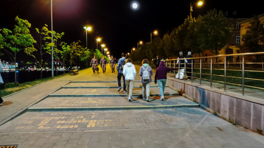 Пешеходы на освещённой набережной в ночное время
