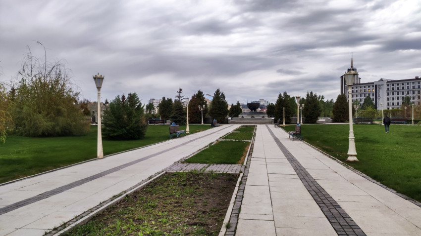 Аллея с фонарями и скамейками в городском парке