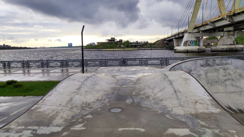 Скейт-площадка на набережной с видом на мост и воду