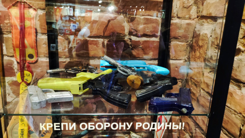Игрушечные пистолеты в витрине на фоне кирпичной стены