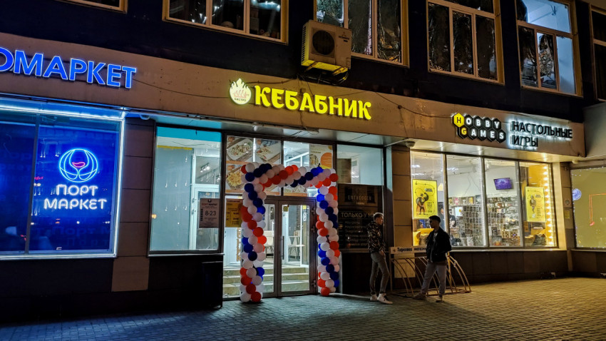 Фасад магазинов Порт Алкомаркет, Кебабник и Hobby Games в вечернее время