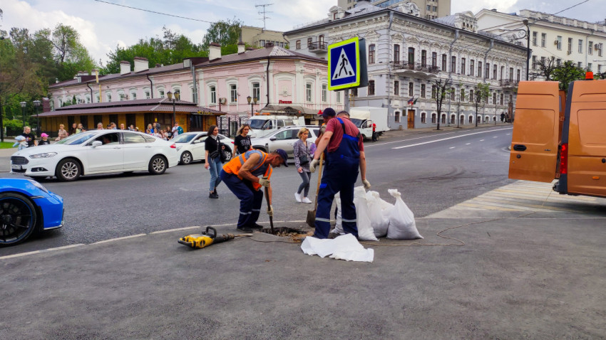 Рабочие ремонтируют дорогу у пешеходного перехода