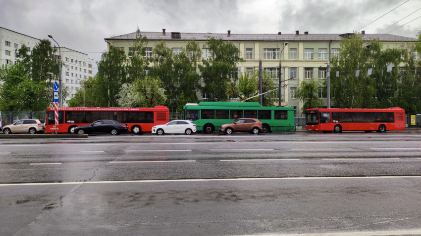 Городской общественный транспорт на фоне здания школы в Казани