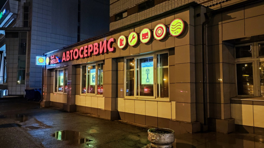 Вид на автомастерскую Shell Helix с яркой вывеской ночью