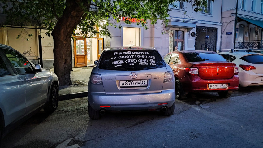 Автомобиль Mazda с рекламой авторазборки припаркован во дворе