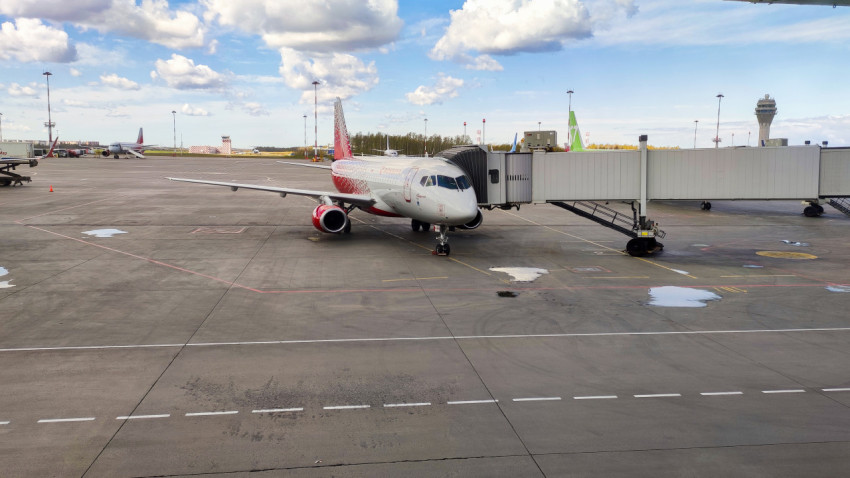Пассажирский самолёт у телетрапа на фоне контрольной вышки