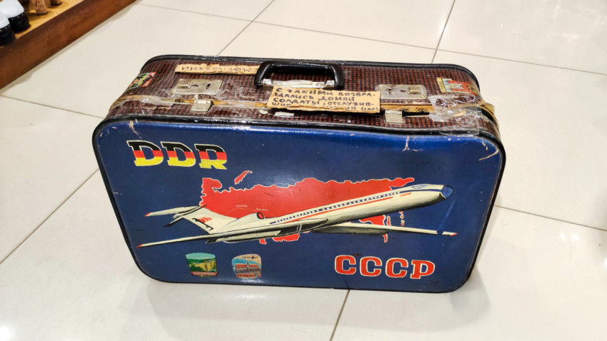 Чемодан с символикой СССР и ГДР на фоне карты