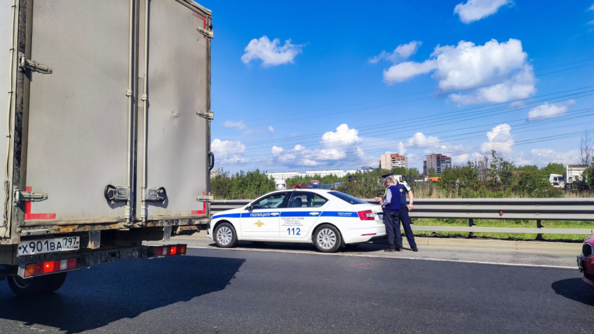 Патрульный автомобиль и сотрудники на обочине магистрали