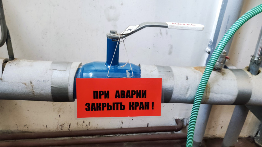 Шаровый кран с табличкой «При аварии закрыть кран!» на трубопроводе