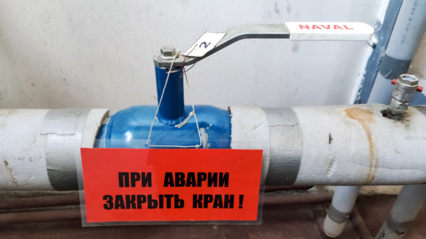Шаровой кран на трубе и предупреждающая табличка