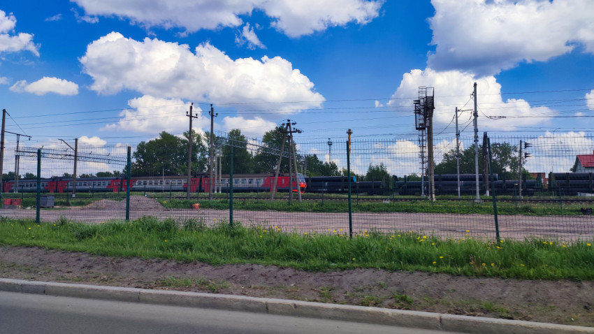 Пригородный электропоезд и грузовой состав за защитным ограждением
