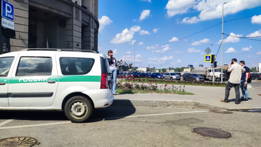 Служебный автомобиль у здания с клумбой