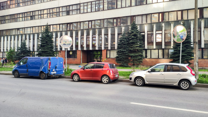 Парковка у фасада с дорожными зеркалами и елями