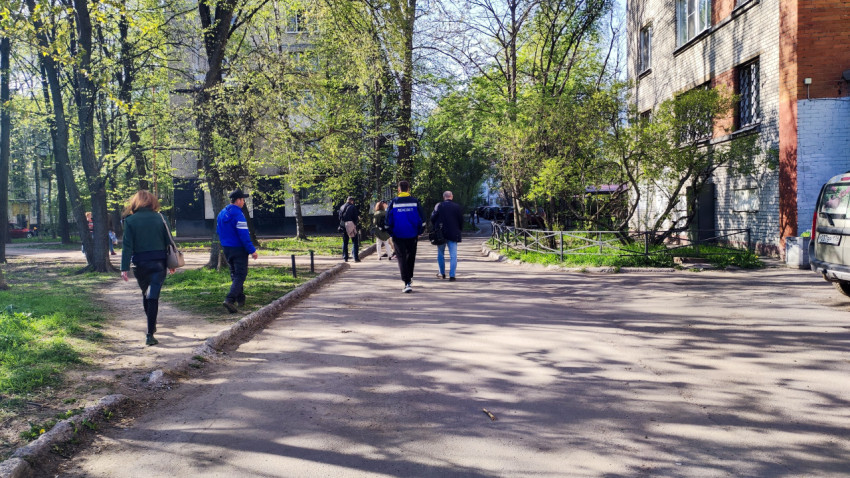 Пешеходы у жилого дома и деревьев во дворе