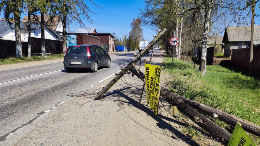 Упавший деревянный столб у дороги с проезжающими машинами
