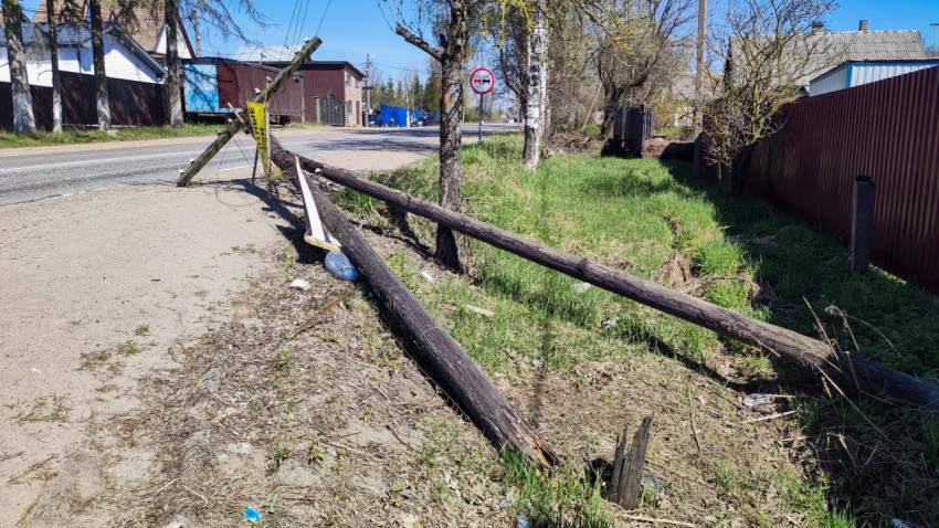 Поваленный деревянный столб линии электропередачи у дороги