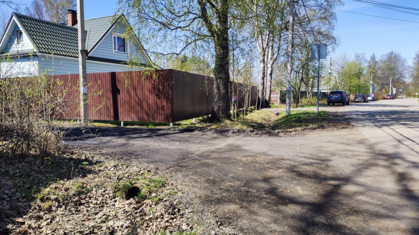 Загородный дом с зелёной крышей и высоким забором