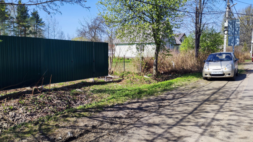 Загородная дорога с автомобилем у зелёного забора