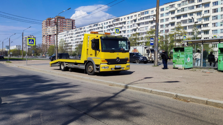 Желтый эвакуатор Mercedes Atego на городской улице