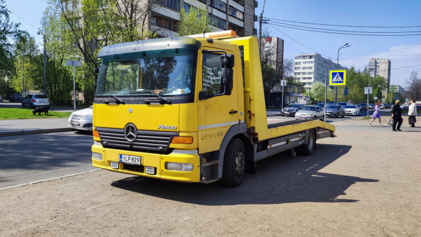 Желтый эвакуатор Mercedes Atego на парковке у жилых домов