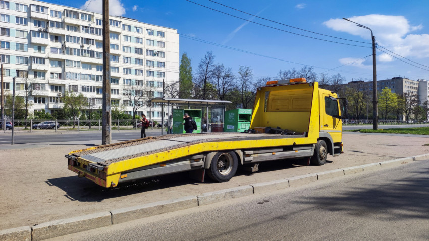 Эвакуатор Mercedes Atego на фоне жилых домов и остановки