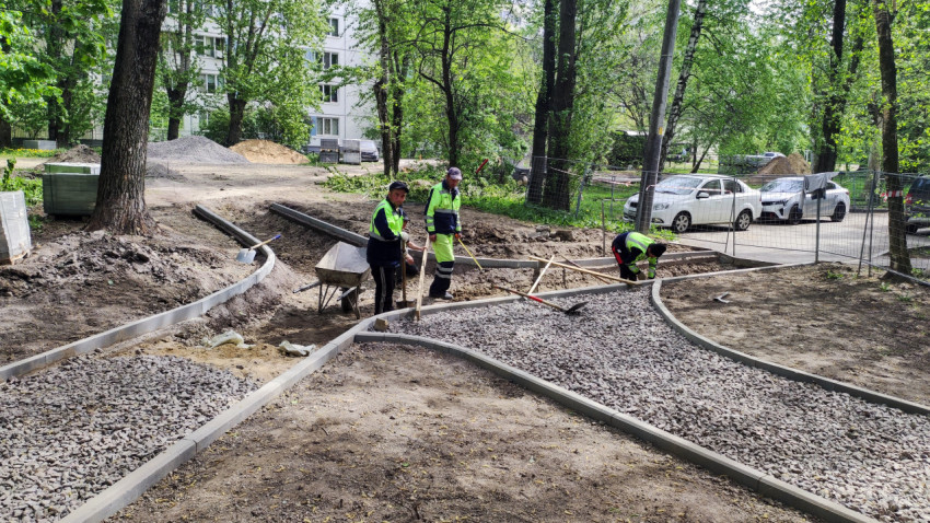 Рабочие укладывают основание тротуарной дорожки