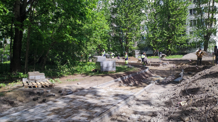 Рабочие укладывают плитку на пешеходной дорожке