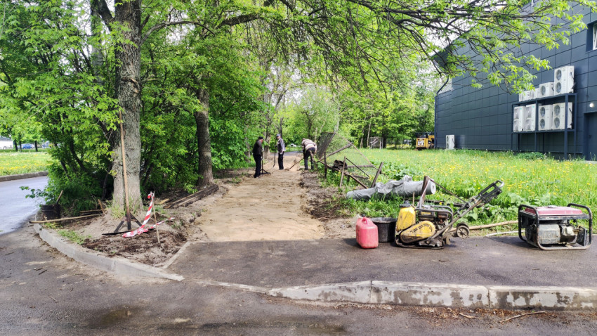 Рабочие укладывают дорожное покрытие в зелёной зоне