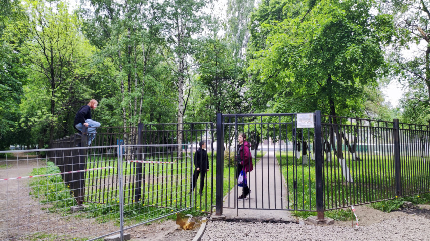 Люди переходят через забор во время ремонта территории