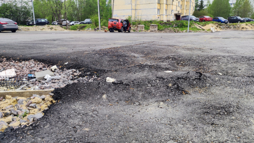 Разрушенное асфальтовое покрытие с выбоинами и щебнем