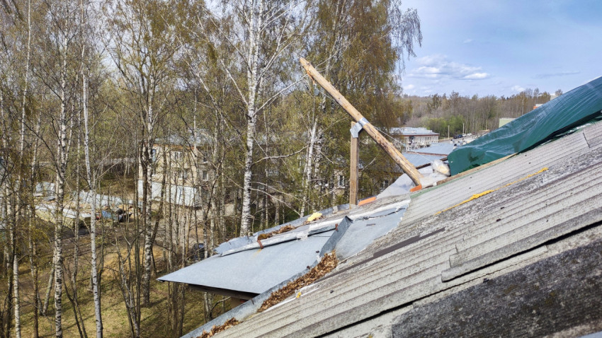 Повреждённая кровля жилого дома среди деревьев