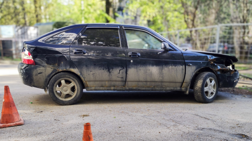 Поврежденный автомобиль Lada Priora сбоку с видимыми вмятинами