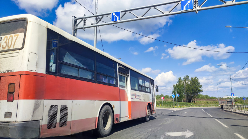 Автобус на перекрёстке под рамной конструкцией с дорожными знаками
