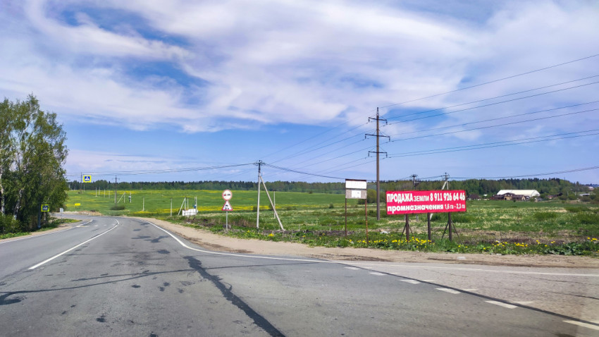 Загородная дорога и рекламный щит о продаже земли